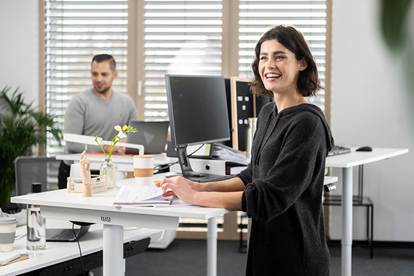 Frau arbeitet am Yaasa Desk Essential mit Notizbuch