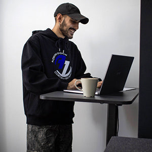 Mann arbeitet im Stehen an einem höhenverstellbaren Schreibtisch und profitiert von den Vorteilen.