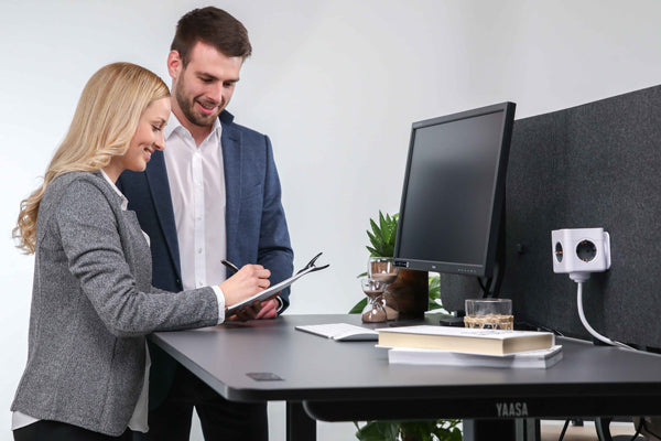 Zwei Personen arbeiten im Stehen am höhenverstellbaren Schreibtisch Desk Pro 2 in Schwarz von Yaasa