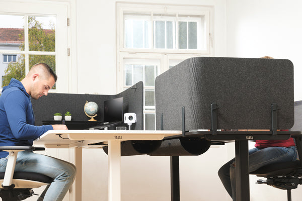 Mann arbeitet im Sitzen an einem höhenverstellbaren Schreibtisch 180 x 80 cm