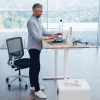 Mann arbeitet im Stehen am Yaasa Desk Pro 2 in Vollholz Eiche/Weiß
