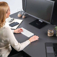 Frau arbeitet an einem Yaasa Desk Pro 2 in der Farbe Dunkelgrau/Schwarz.