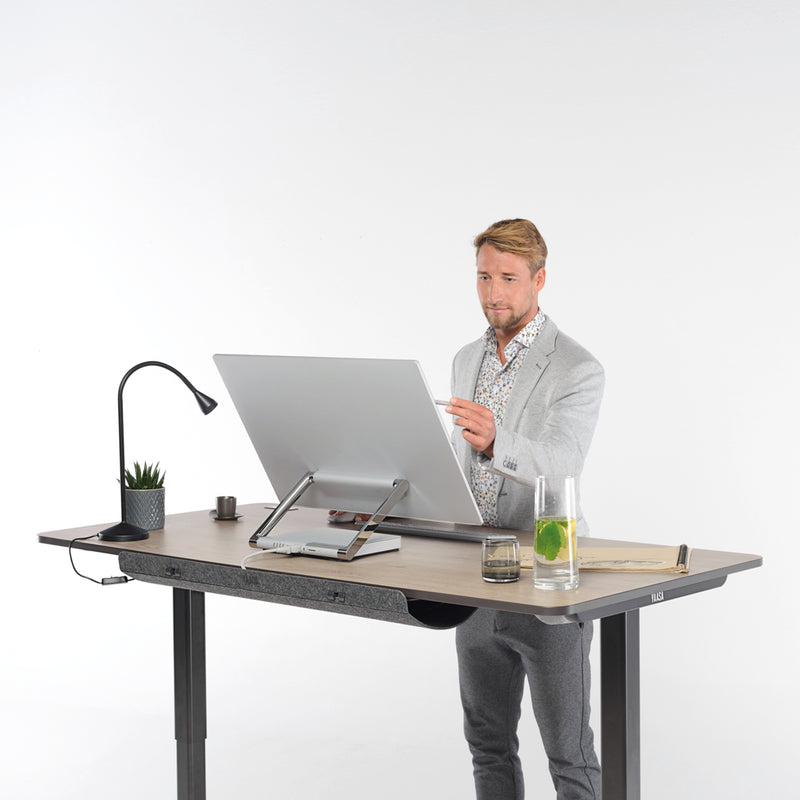 Mann arbeitet im Stehen an einem Desk Pro 2 in der Farbe Eiche.